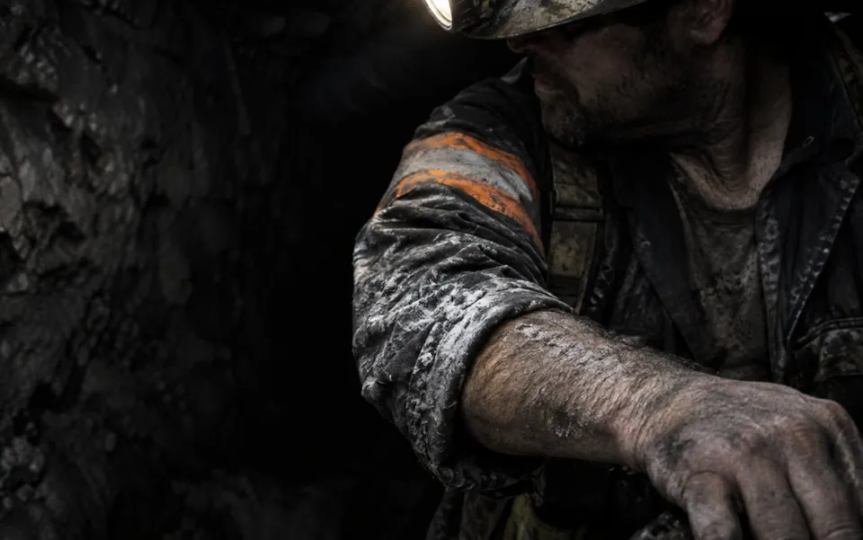 Underground miner at shift end, salt staining dried across his sleeve